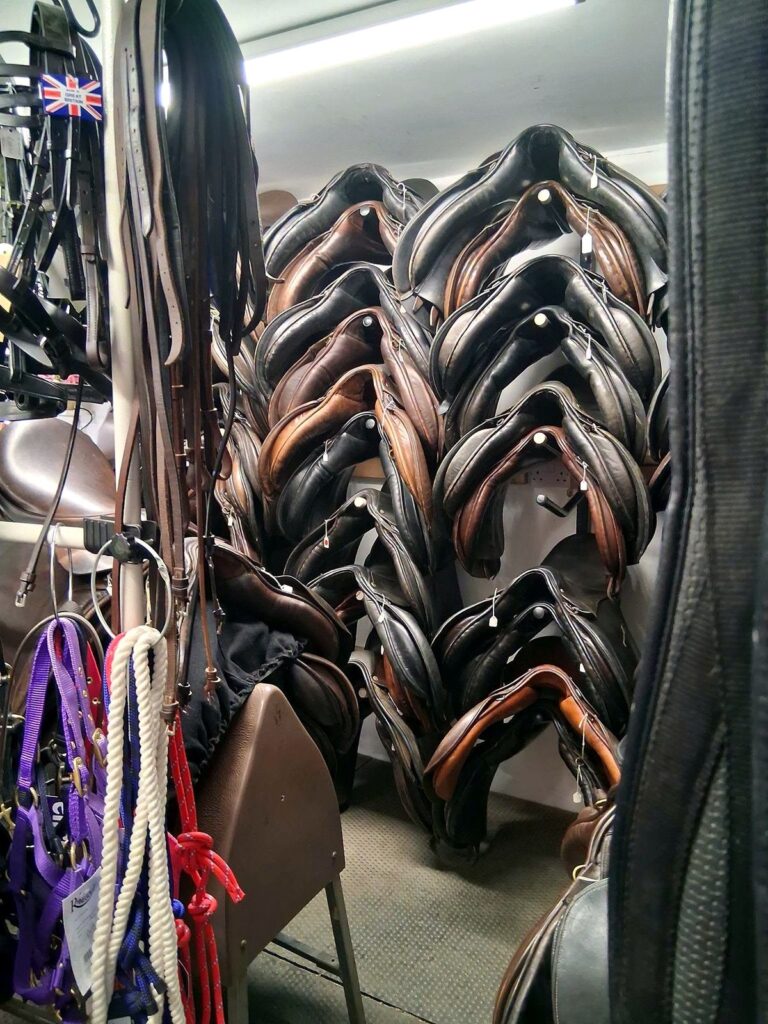 Second-hand saddles stacked on a stand at The Newark Saddler